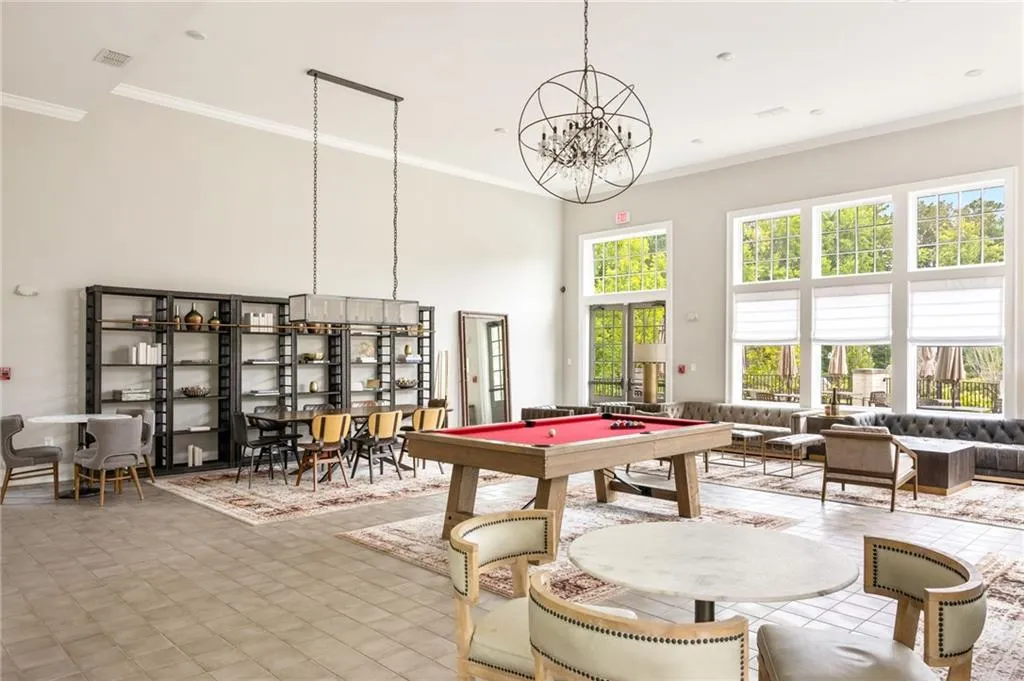 Game room with crown molding, visible vents, a towering ceiling, and a notable chandelier