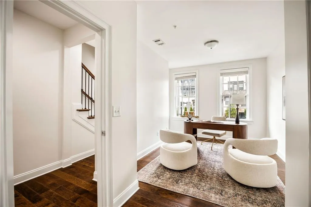 Home office with dark wood-style flooring, visible vents, and baseboards