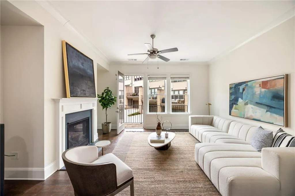 Living area featuring dark wood-style floors, baseboards, ornamental molding, and a glass covered fireplace