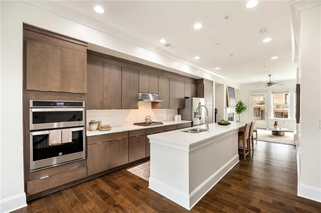 Kitchen featuring light countertops, appliances with stainless steel finishes, dark wood-type flooring, a sink, and under cabinet range hood