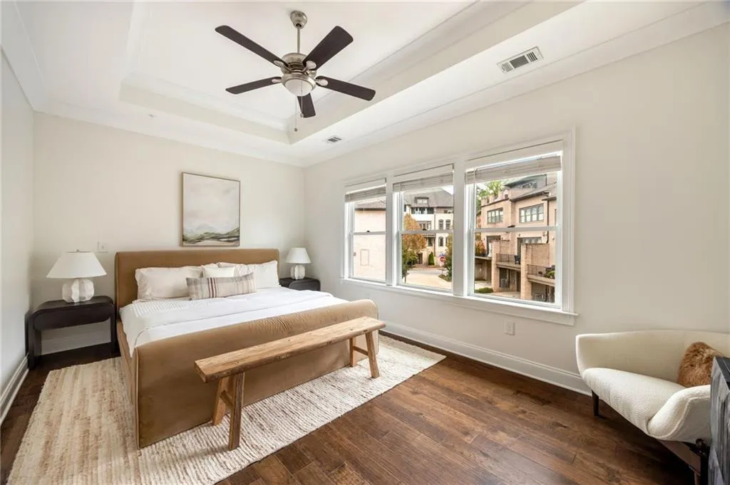 Bedroom featuring baseboards, visible vents, a raised ceiling, dark wood-style floors, and ceiling fan