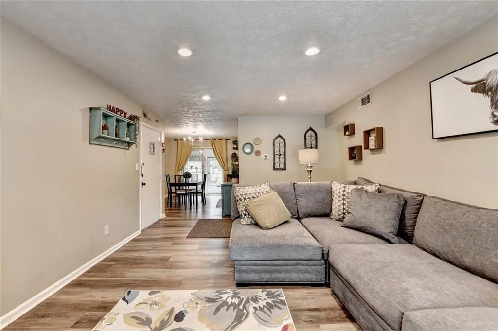 Living room featuring recessed lighting, light wood-type flooring, baseboards, and a textured ceiling