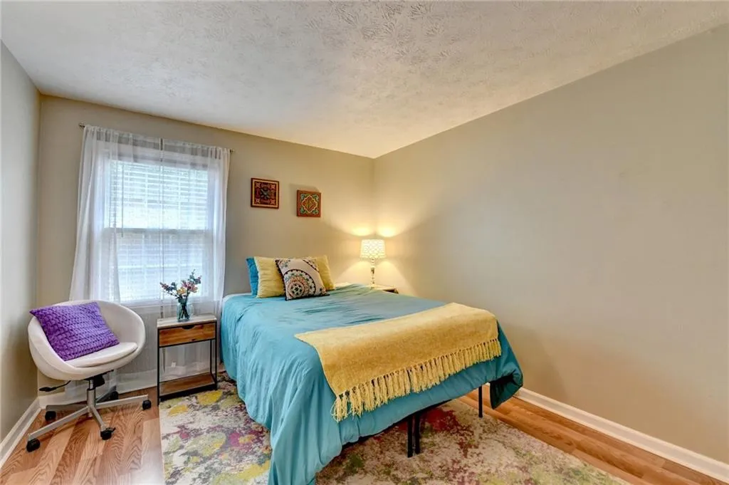 Bedroom with baseboards, wood finished floors, and a textured ceiling