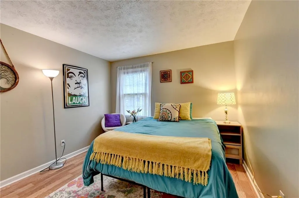Bedroom featuring light wood finished floors, baseboards, and a textured ceiling