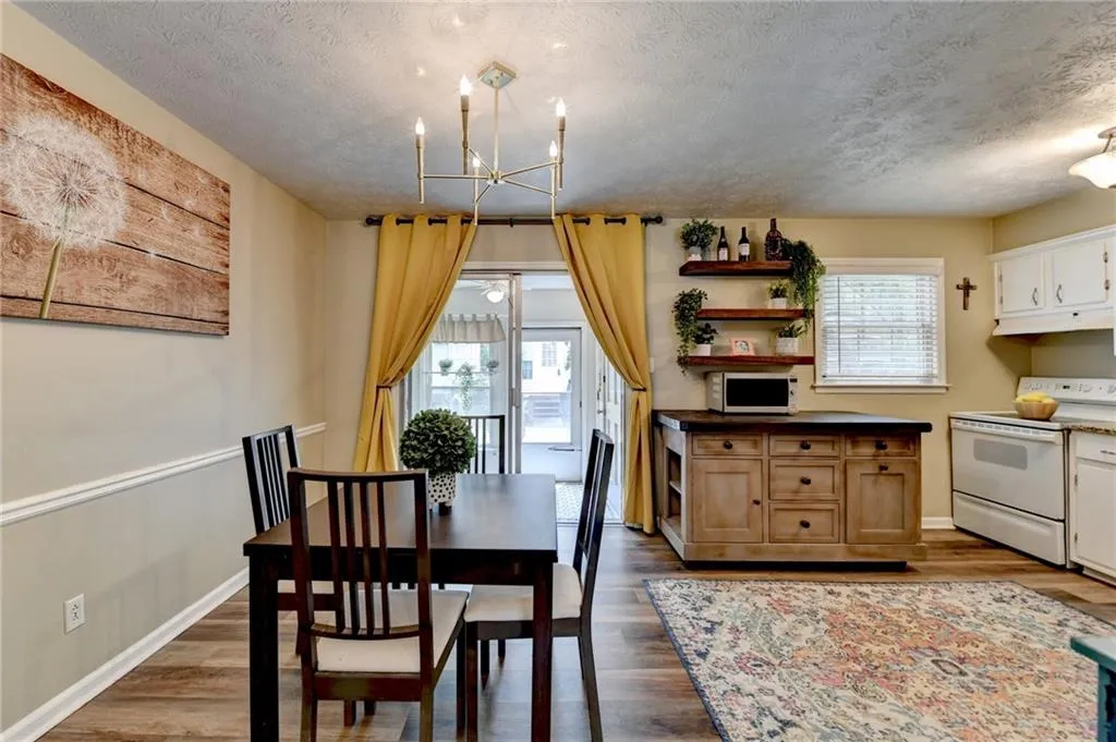 Dining room featuring a chandelier, a textured ceiling, dark wood-style flooring, and baseboards