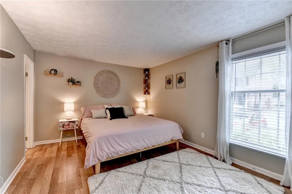 Bedroom featuring wood finished floors, multiple windows, a textured ceiling, and baseboards
