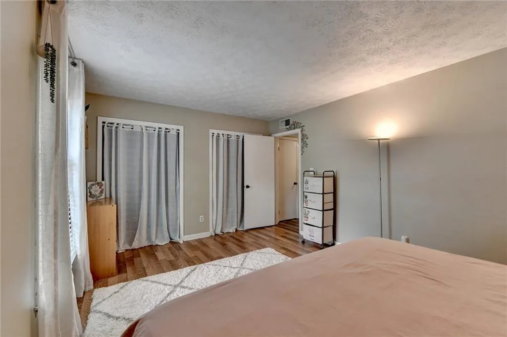 Bedroom with wood finished floors, a textured ceiling, and baseboards
