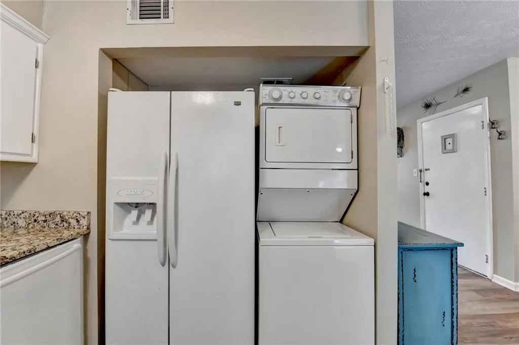Washroom featuring stacked washer / dryer and wood finished floors