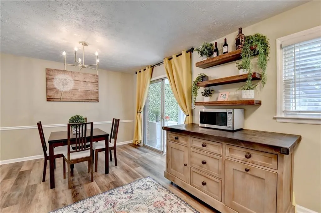 Dining space featuring a textured ceiling, a chandelier, light wood-type flooring, and baseboards