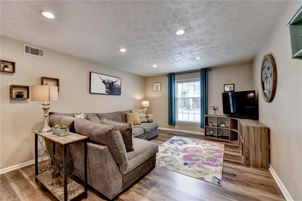 Living room featuring wood finished floors, a textured ceiling, recessed lighting, and baseboards