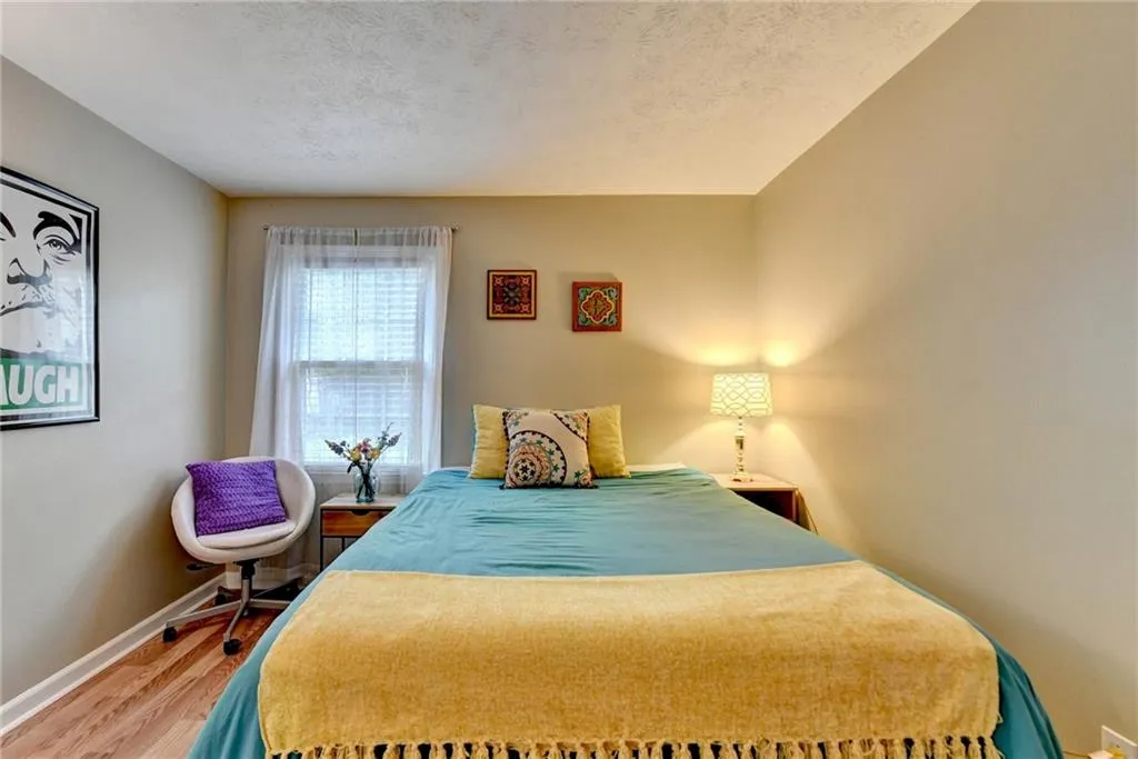 Bedroom with wood finished floors, baseboards, and a textured ceiling