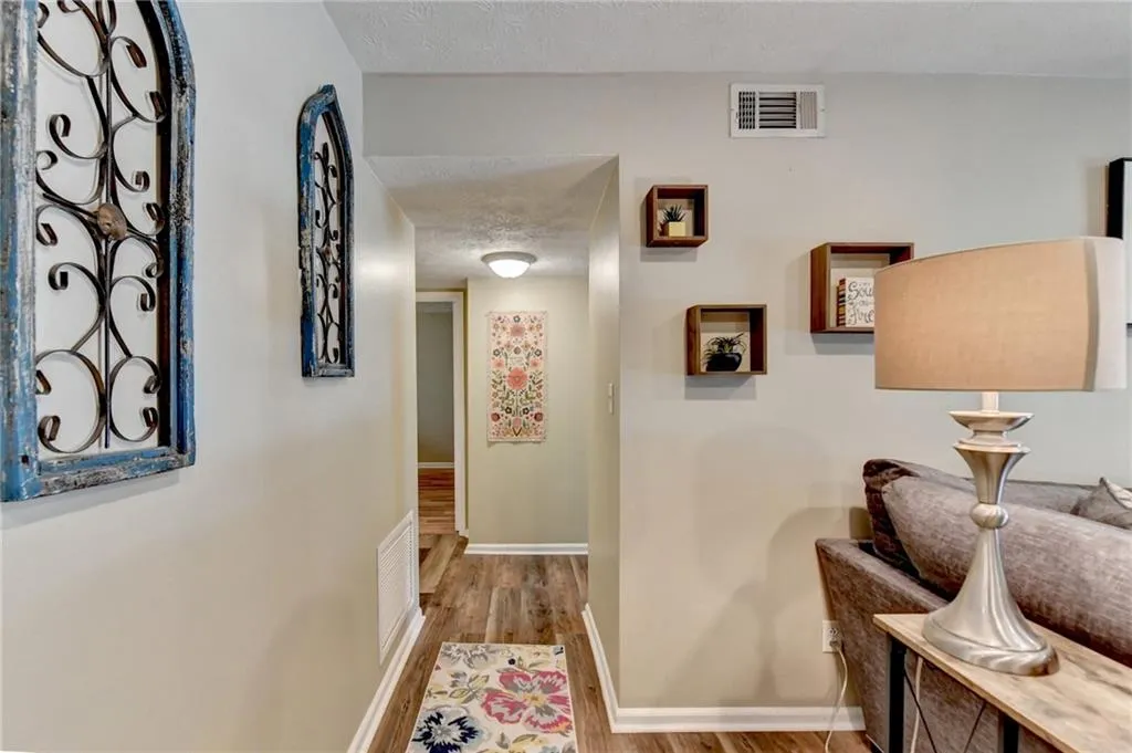 Hall with wood finished floors, baseboards, and a textured ceiling