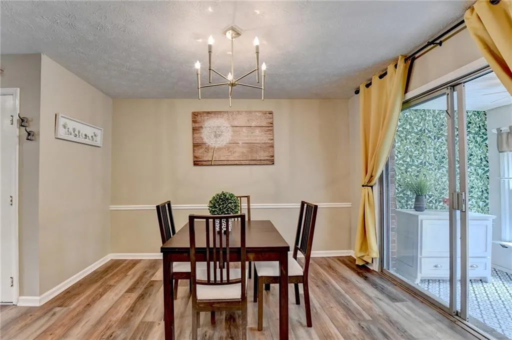 Dining space featuring light wood-style flooring, a chandelier, baseboards, and a textured ceiling