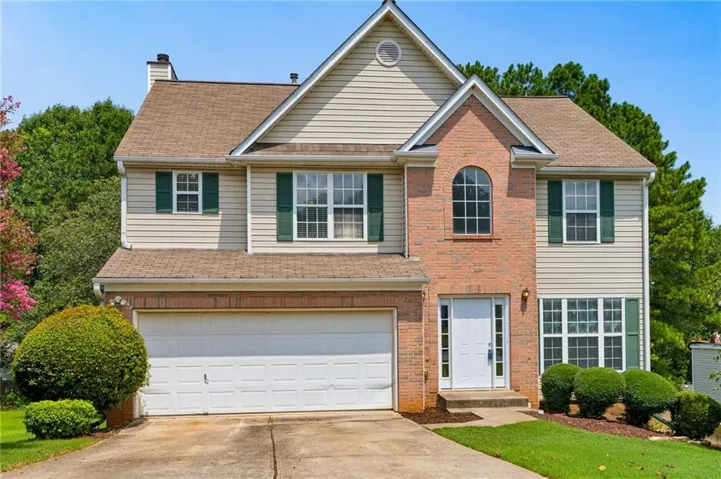 Traditional two-story residence featuring a brick and siding exterior, an arched window, and a prominent two-car garage