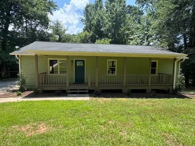 Single-story residence featuring light green siding and a covered front porch with railing