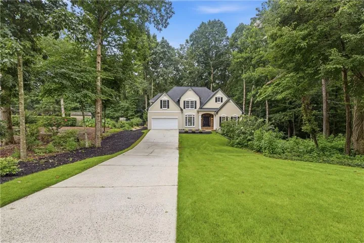 Two-story residence featuring a light-toned exterior, dark shutters, and a prominent front entrance with a dark door