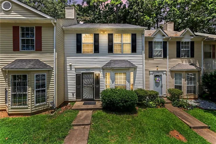 Two-story townhouse with light-colored siding and dark shutters