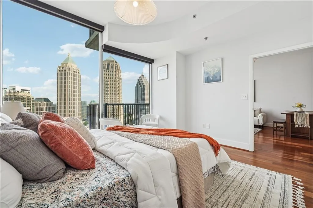Bedroom with wood finished floors, a skyline view, baseboards, access to exterior, and expansive windows