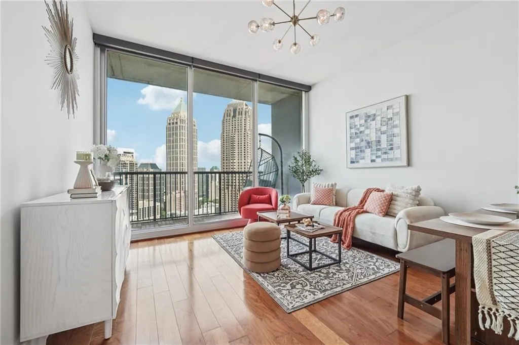 Living room with floor to ceiling windows, wood finished floors, a chandelier, and a view of skyline