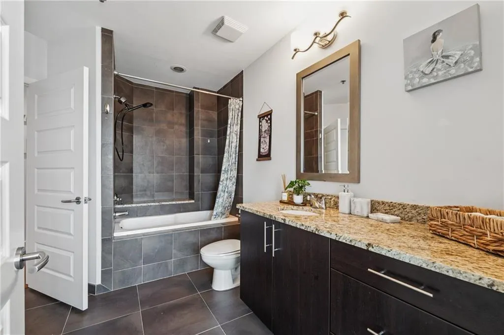 Bathroom featuring tile patterned floors, vanity, tiled shower / bath, and toilet