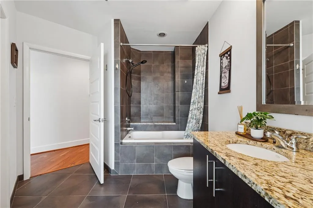 Full bathroom featuring tiled shower / bath combo, tile patterned floors, vanity, toilet, and baseboards