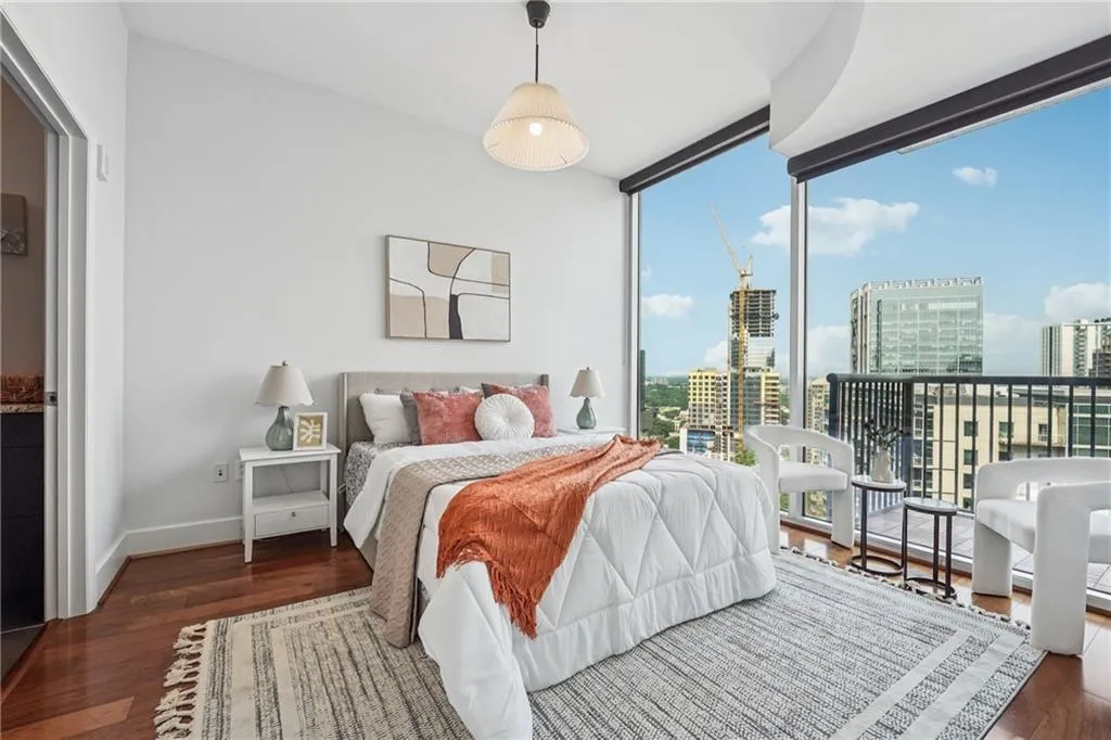 Bedroom featuring a city view, floor to ceiling windows, wood finished floors, and baseboards