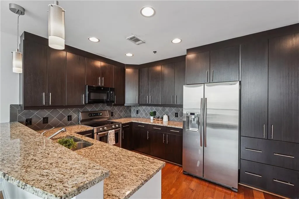 Kitchen with stainless steel appliances, a sink, a peninsula, dark brown cabinetry, and recessed lighting