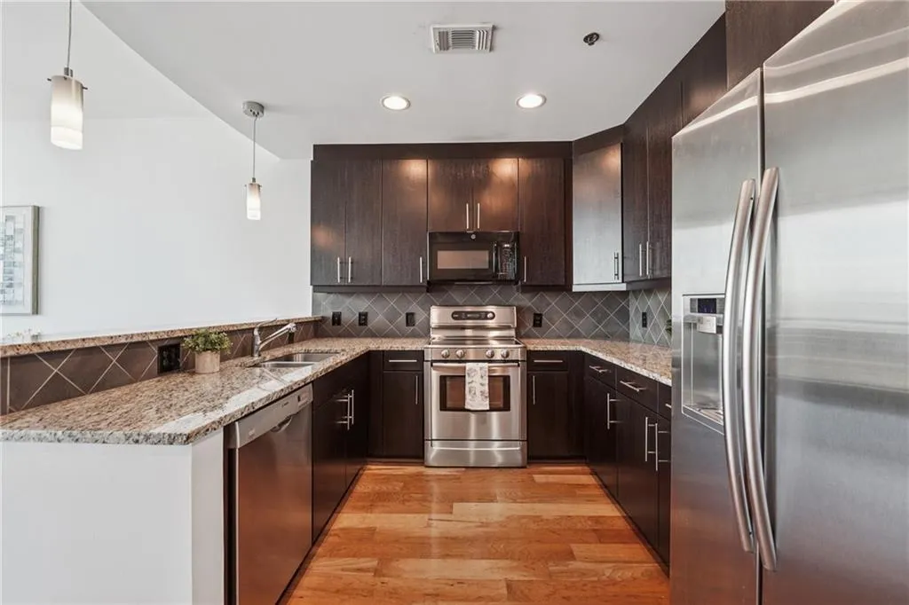 Kitchen with stainless steel appliances, light wood-style flooring, a sink, dark brown cabinetry, and recessed lighting