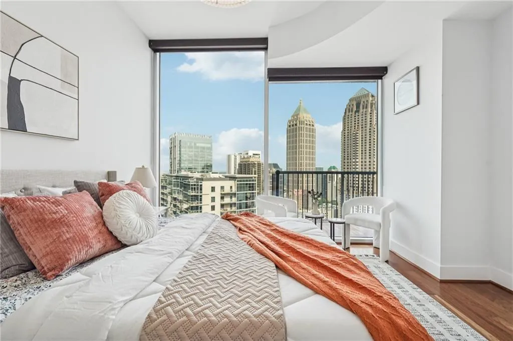 Bedroom with floor to ceiling windows, multiple windows, wood finished floors, a skyline view, and baseboards
