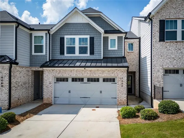 Modern townhouse exterior featuring light-colored brick, gray siding, and shake accents