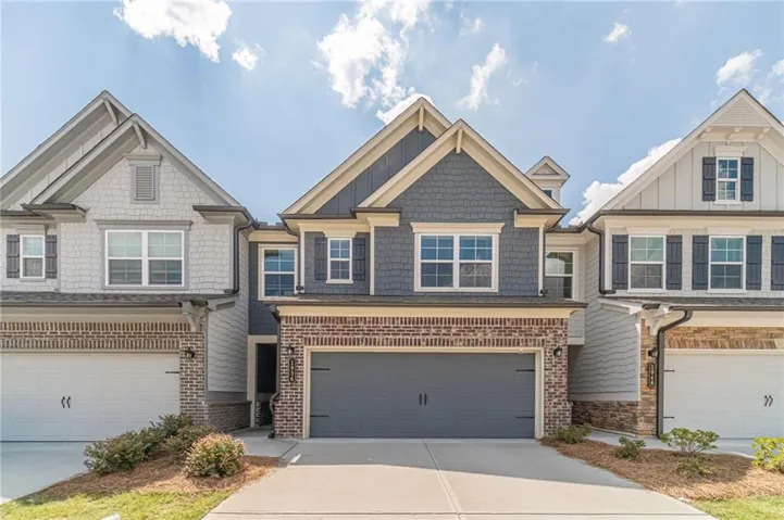 Stone and brick exterior with shake siding accents, two-car garage, and a concrete driveway