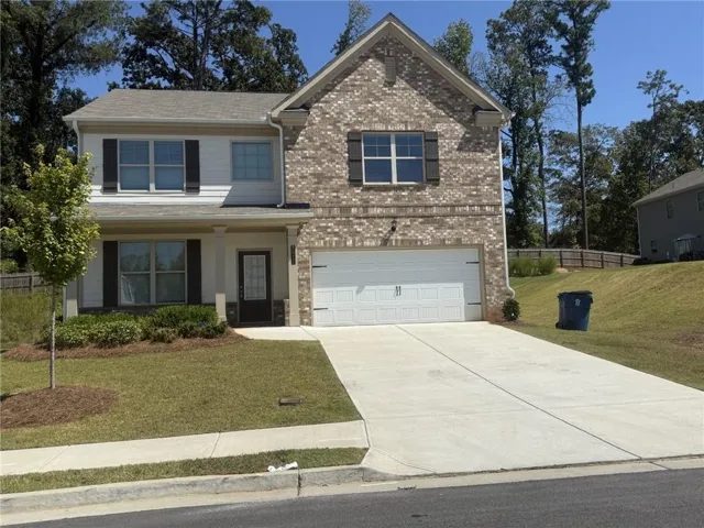 Brick and siding exterior featuring a two-car garage, concrete driveway, and front entry with sidelights