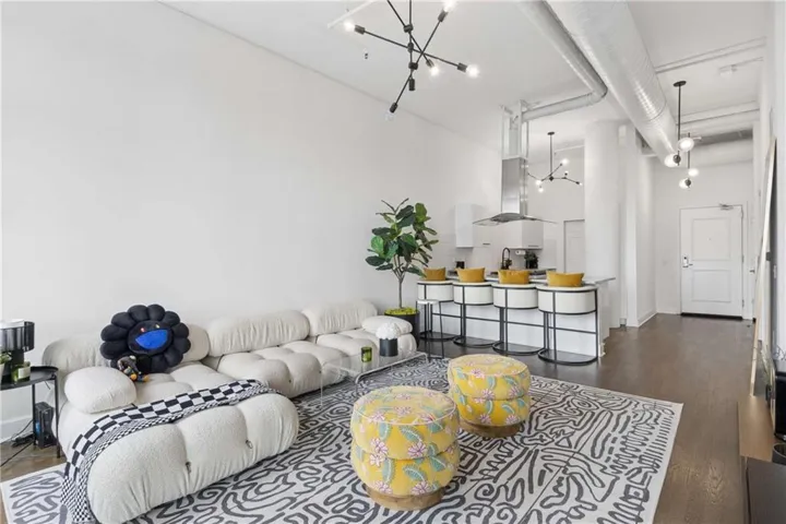 Modern open-concept living space featuring white walls, Hardwood flooring, and contemporary pendant lighting