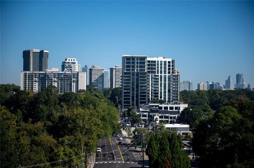 Urban landscape featuring a high-density skyline, multi-story residential towers, dense mature canopy, and a public thoroughfare