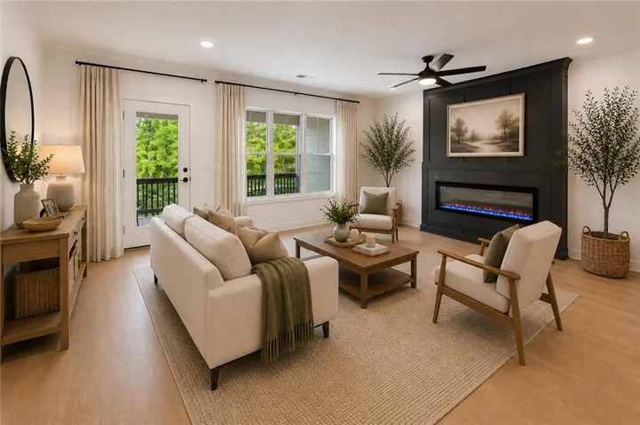 Photo is virtually staged. A spacious family room designed for comfort and connection, featuring a triple window and glass door to the back deck with calming tree views. The space is anchored by a slate fireplace surround with a craftsman-style accent wall, complemented by a modern black ceiling fan.