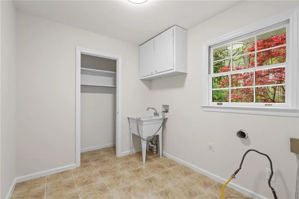Walk-in laundry room with utility sink and additional storage