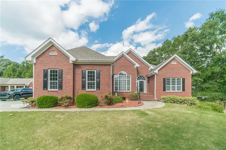 Brick exterior with multiple gables, arched entry, arched window, and front lawn