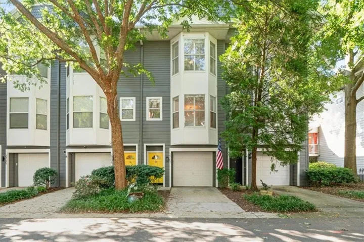 Contemporary townhome exterior with gray siding, white bay windows, and attached garage