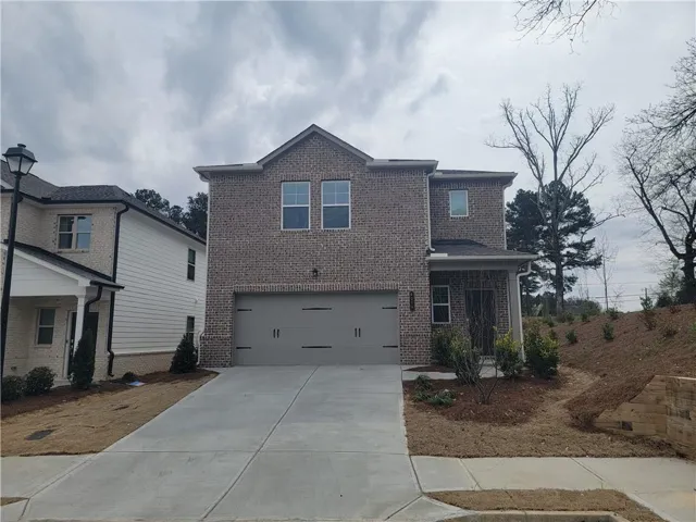 Brick facade home featuring a two-car garage, covered entry, and concrete driveway