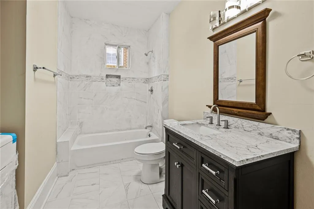 Full bathroom with bathing tub / shower combination, vanity, and light marble finish flooring