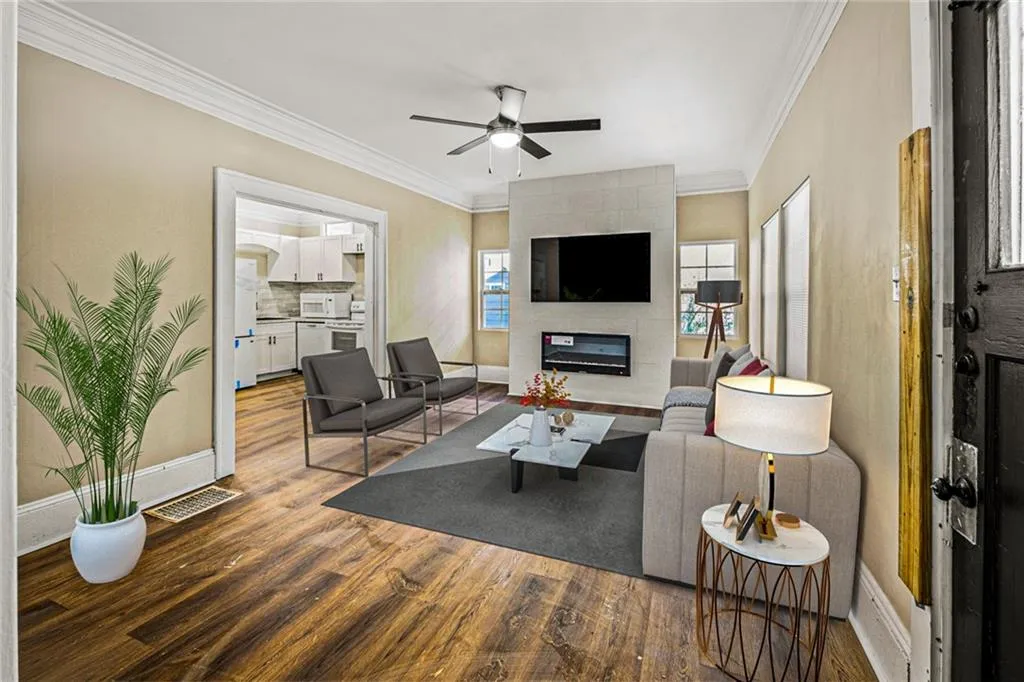 Living room with wood finished floors, crown molding, a tile fireplace, and ceiling fan
