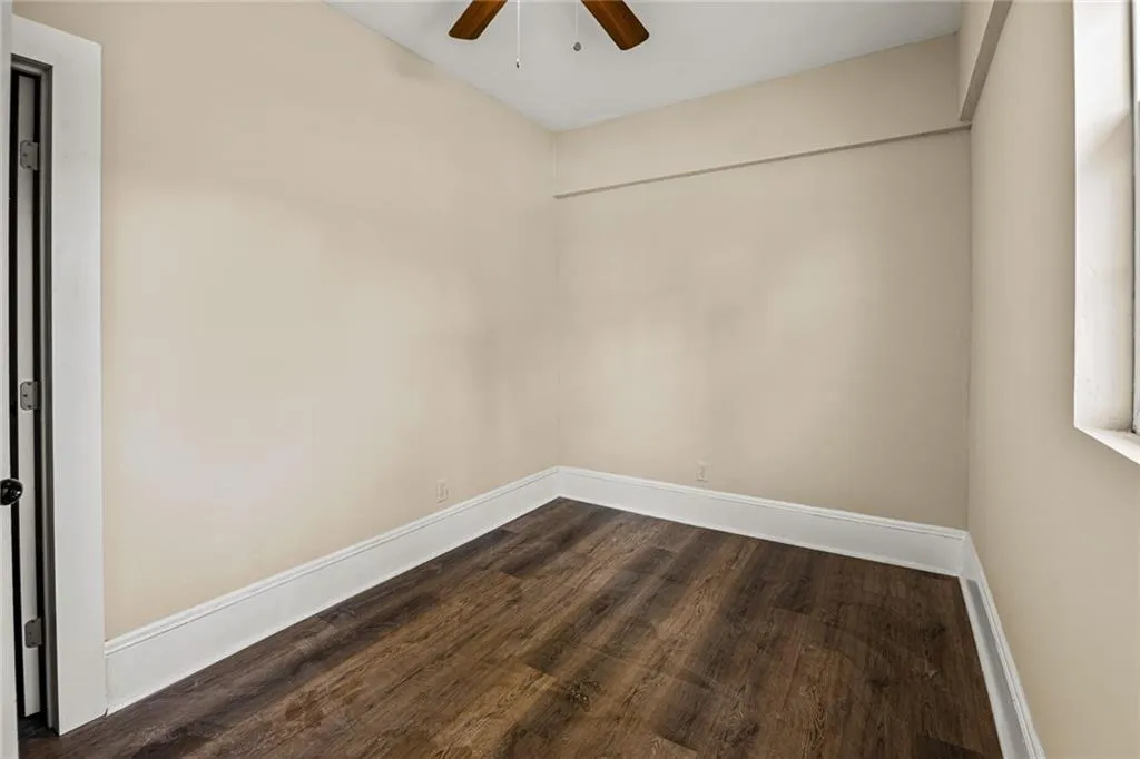 Spare room featuring dark wood-style flooring and a ceiling fan
