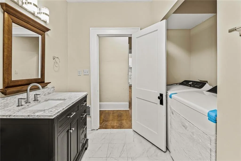 Washroom with light marble finish floors and washing machine and clothes dryer