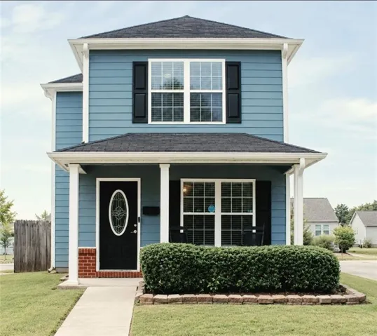 Two-story residence with blue siding, a dark shingle roof, and a covered porch