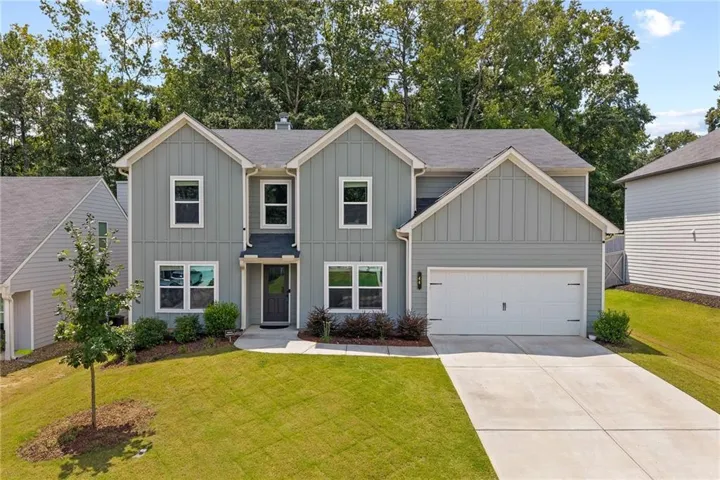 Light gray siding exterior with white trim, a dark gray shingle roof, a two-car garage, an asphalt driveway, and a manicured lawn