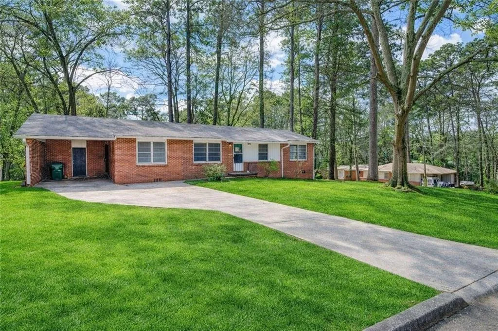 Ranch-style home featuring concrete driveway, brick siding, and a front yard
