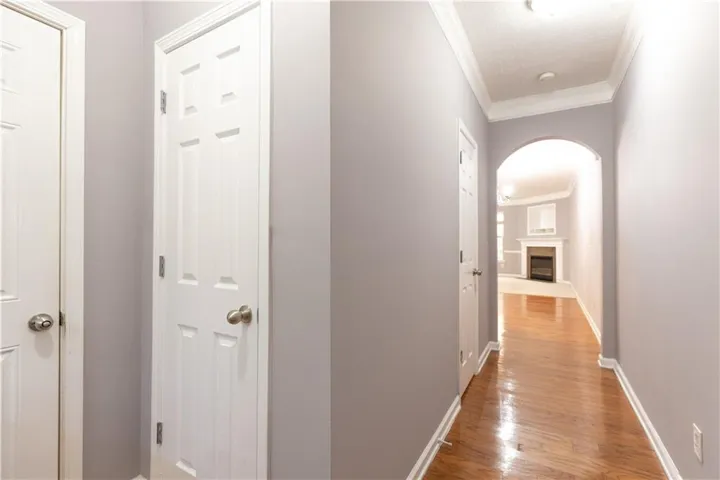 Hardwood flooring extends throughout the hallway, featuring crown molding and an arched doorway