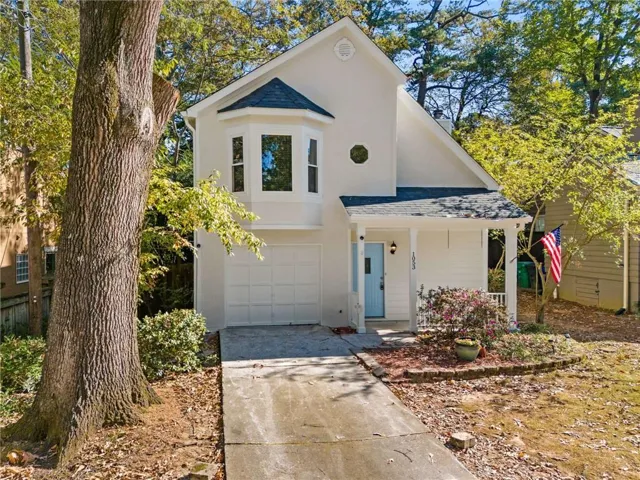 Cream stucco exterior with a prominent bay window, attached garage, covered front porch, and a light blue entry door