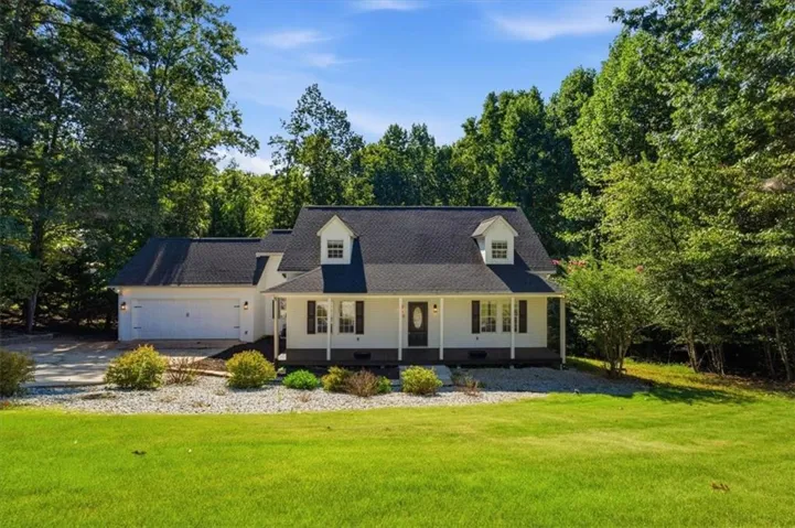 Traditional-style home featuring a covered front porch, dormer windows, and an attached two-car garage