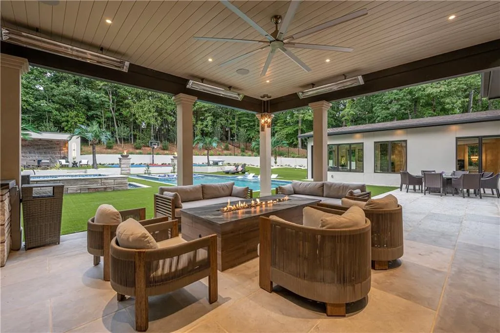 space featuring a built-in outdoor kitchen, patio heaters, ceiling fan, and linear fire table
